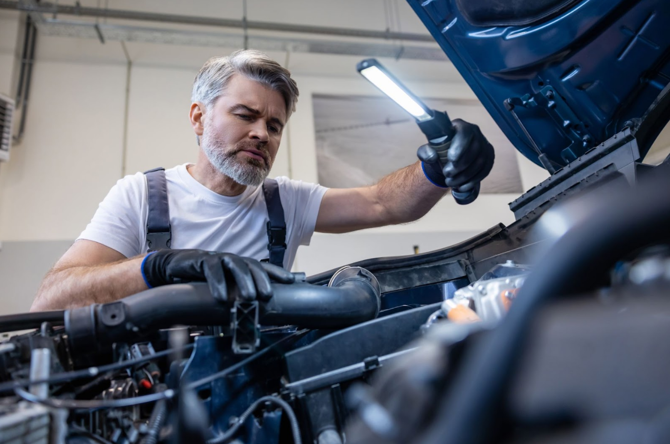 Mechanic inspects engine bay with light—troubleshooting issue after the vehicle’s engine locked up.