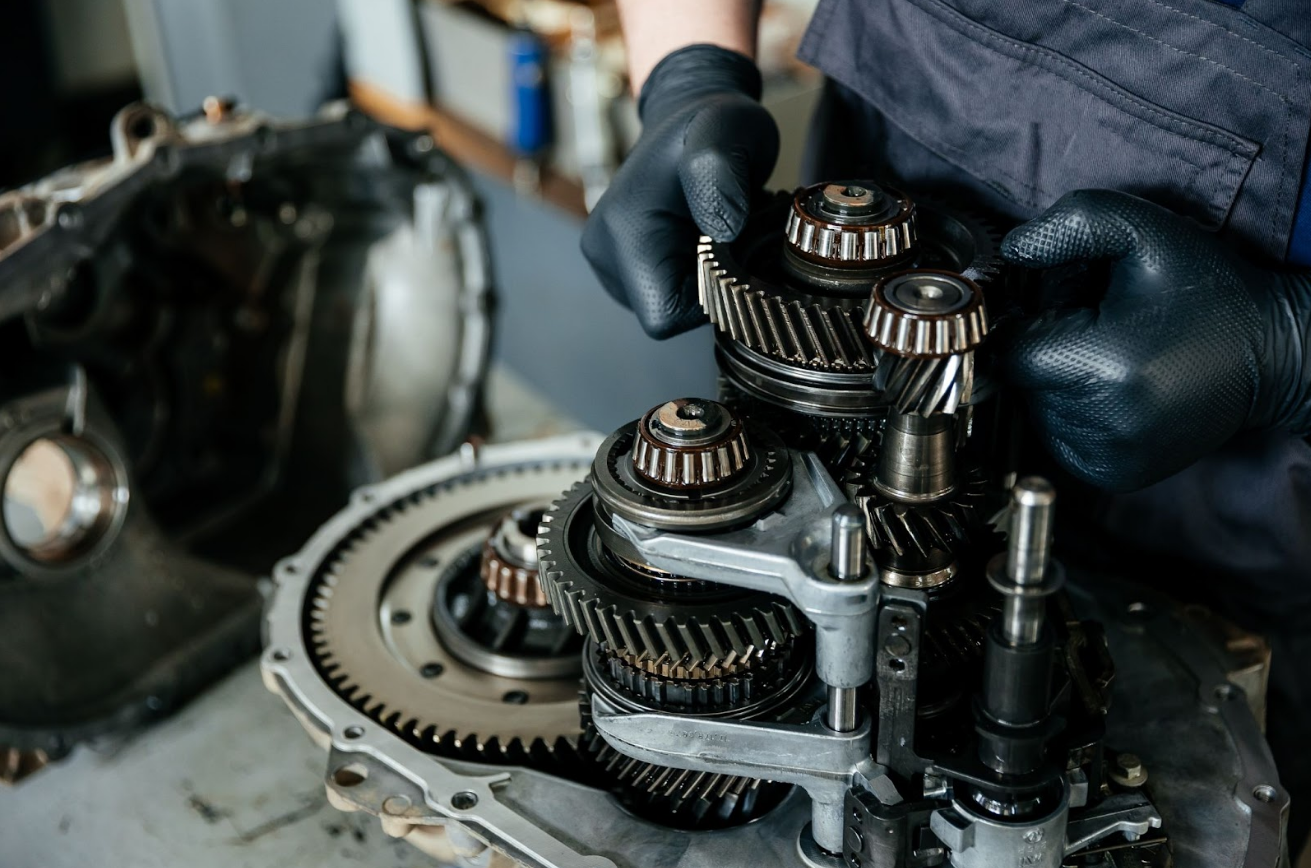Mechanic working on disassembled gears and bearings, illustrating f-150 transmission problems during repair.