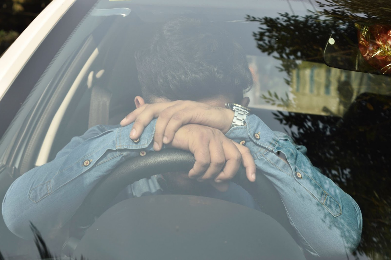 Frustrated driver slumped over steering wheel, symbolizing 2024 Lincoln Navigator problems and ongoing vehicle issues. 