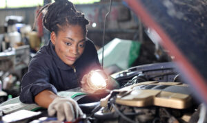  Mechanic inspecting engine with work light while diagnosing 2023 Hyundai Tucson engine problems. 